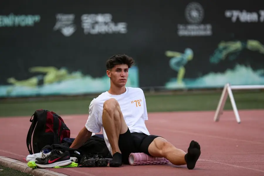 Athlete sitting on a running track beside a foam roller after training